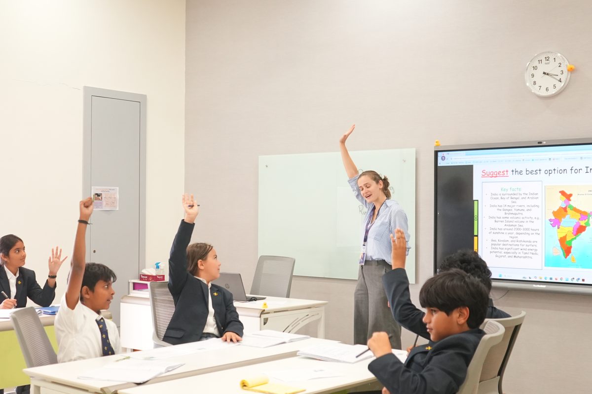 A lesson in progress, with pupils raising their hands